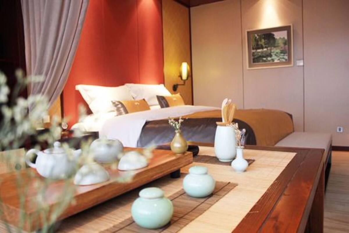 A hotel room with a bed, bedside table, and a wall-mounted lamp.