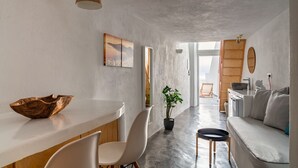 A modern kitchen with a wooden countertop, white chairs, and a potted plant. - Akron Cliff Suite (Santorini)