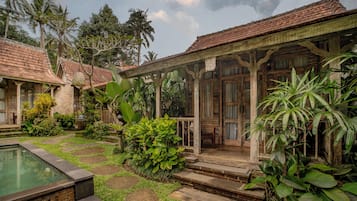 Uma casa de madeira tradicional com varanda coberta, piscina e vegetação tropical exuberante.