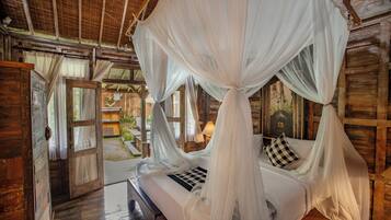 A wooden room with a bed under a canopy, a door leading outside, and a rustic interior.