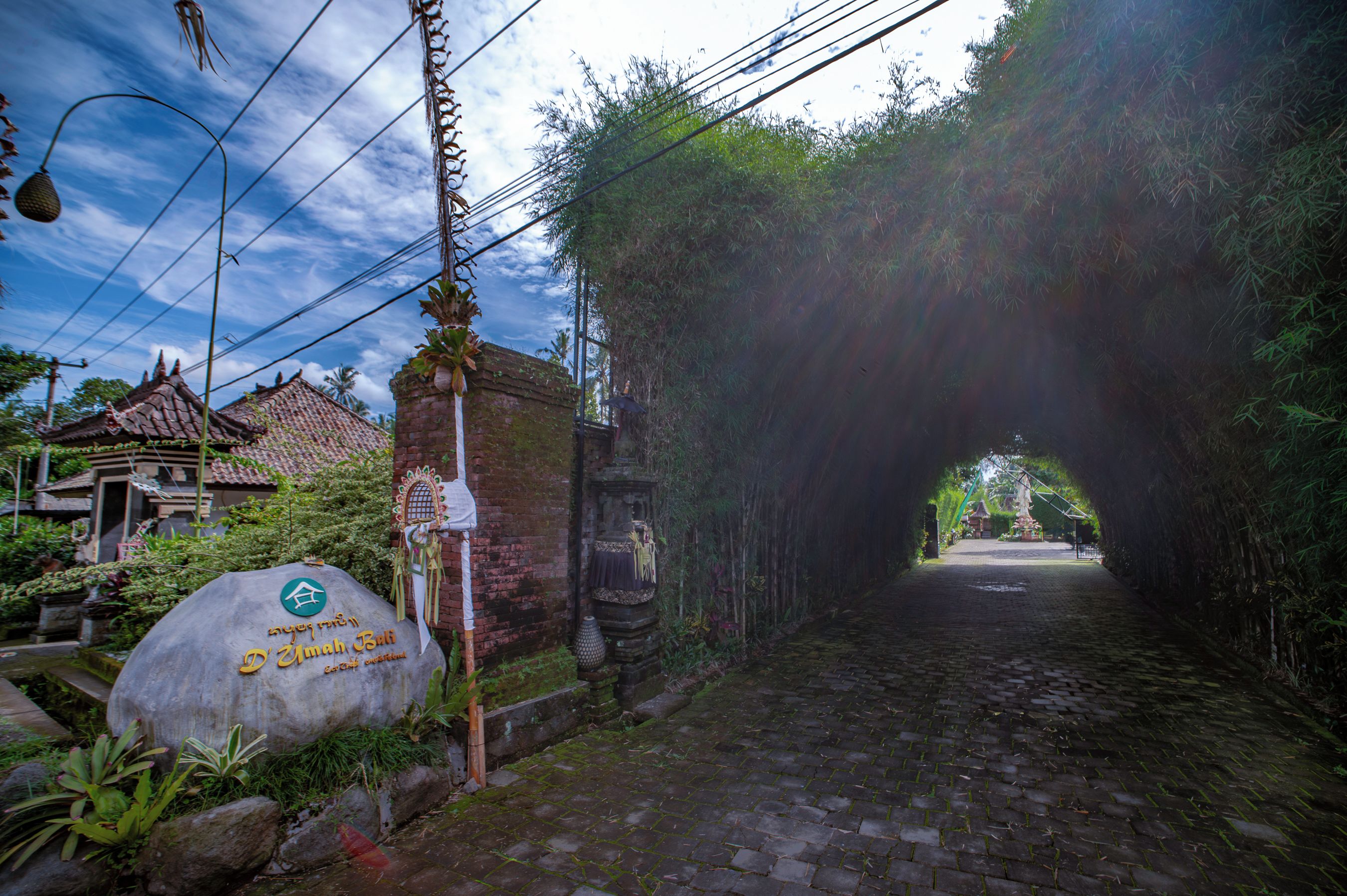 A cobblestone street leading to a traditional building with a sign indicating 'D'Yamah Bali'.