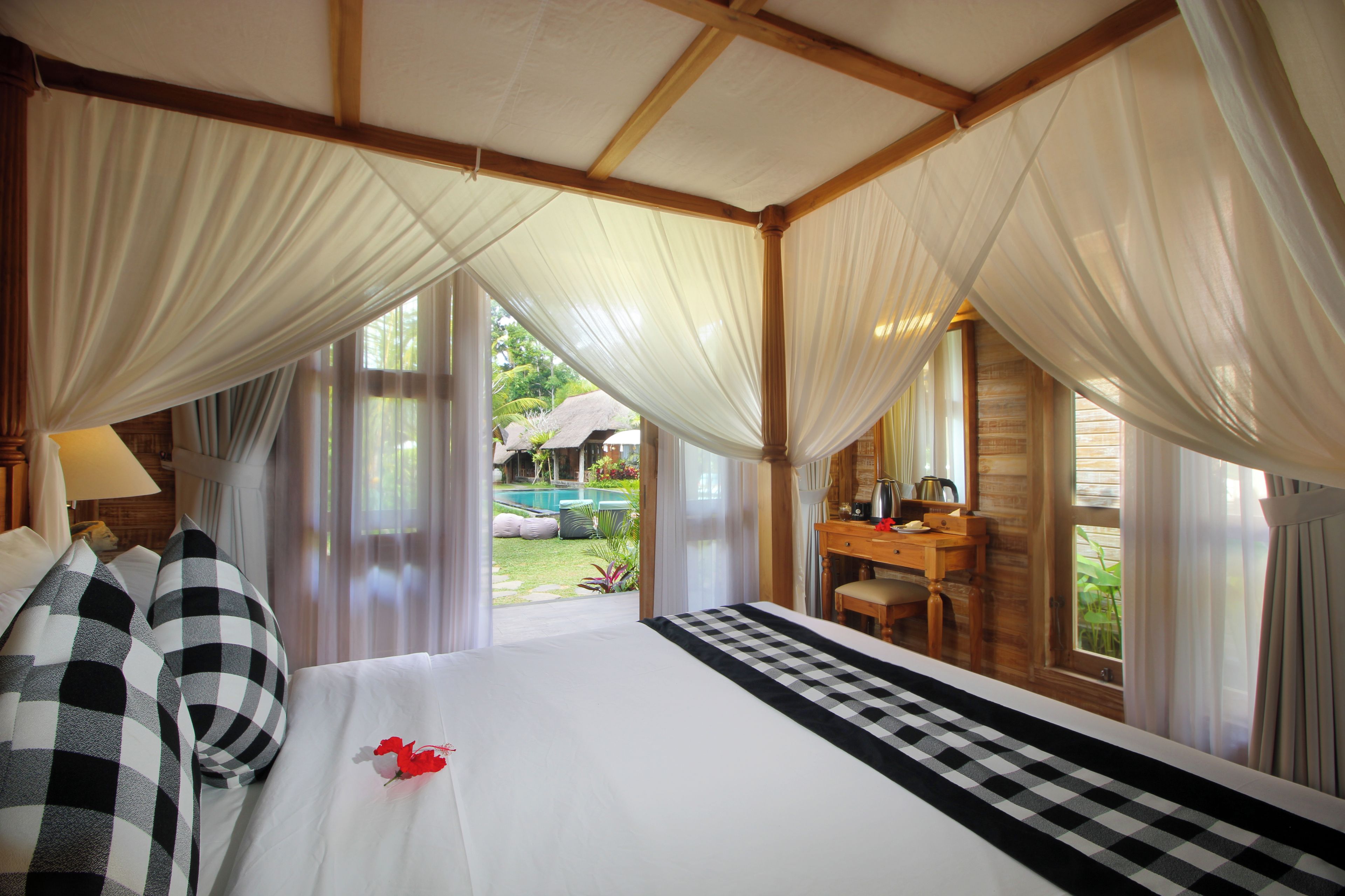Un dormitorio con una cama grande, un escritorio y vistas a una piscina y jardín.