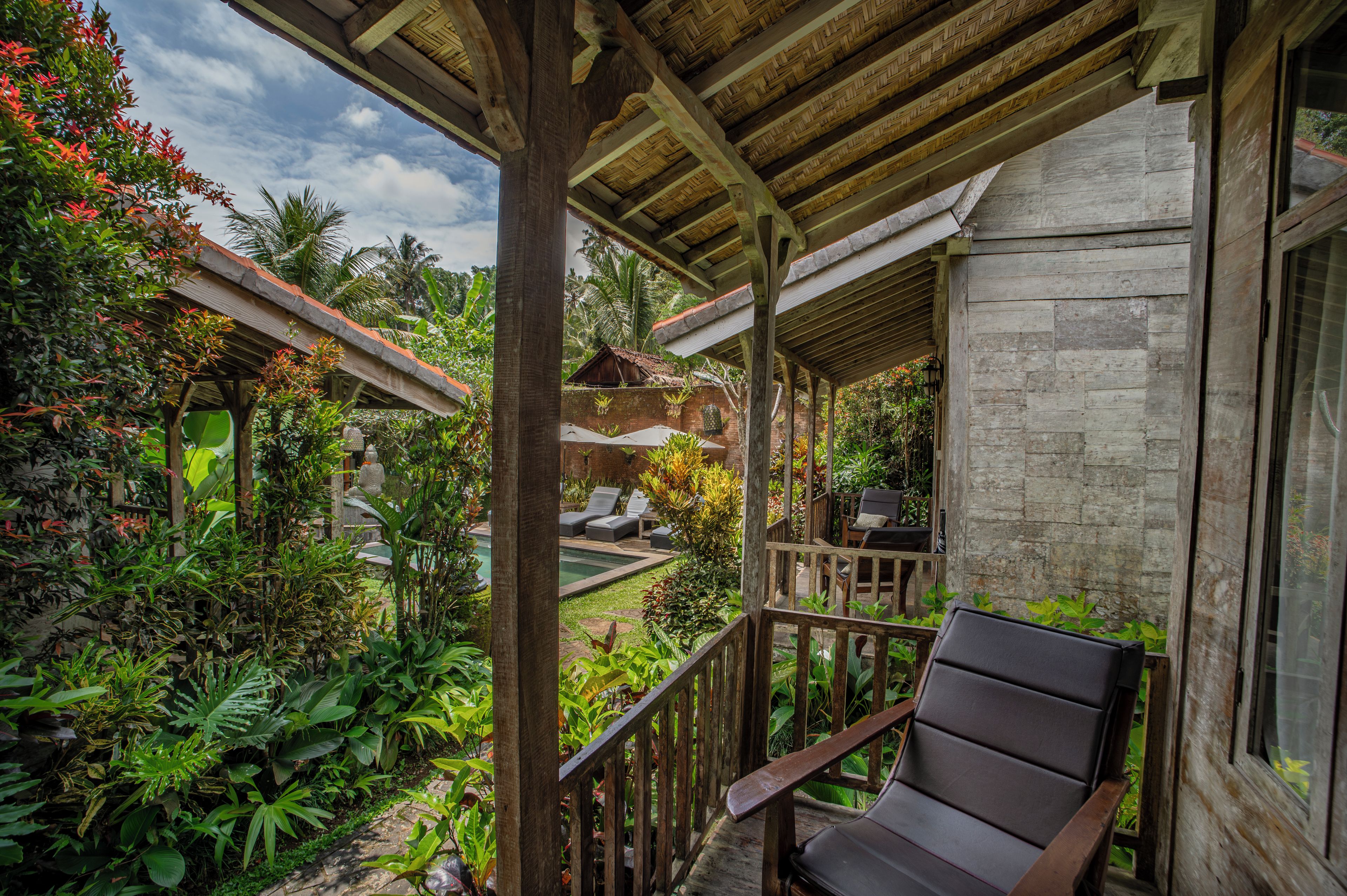 A wooden balcony with a view of a pool and lush greenery.