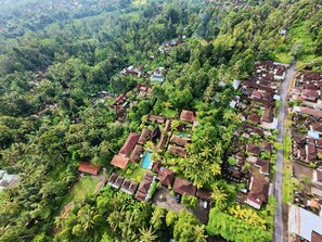 An aerial view of a residential area with houses, a swimming pool, and dense greenery. - De Umah Bali Eco Tradi Home (Tembuku)