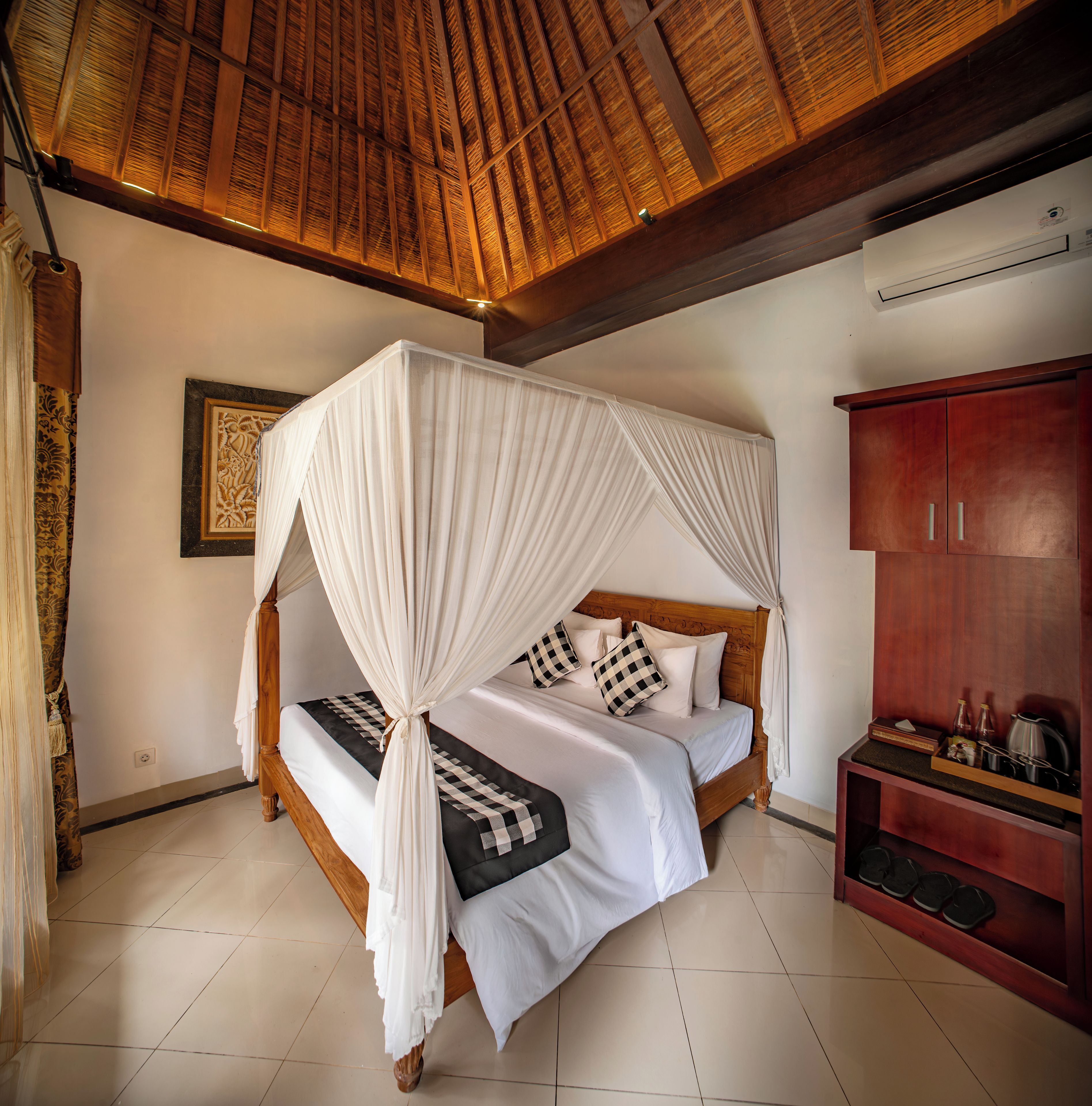 A bed with a canopy, a wooden wardrobe, and a tiled floor.