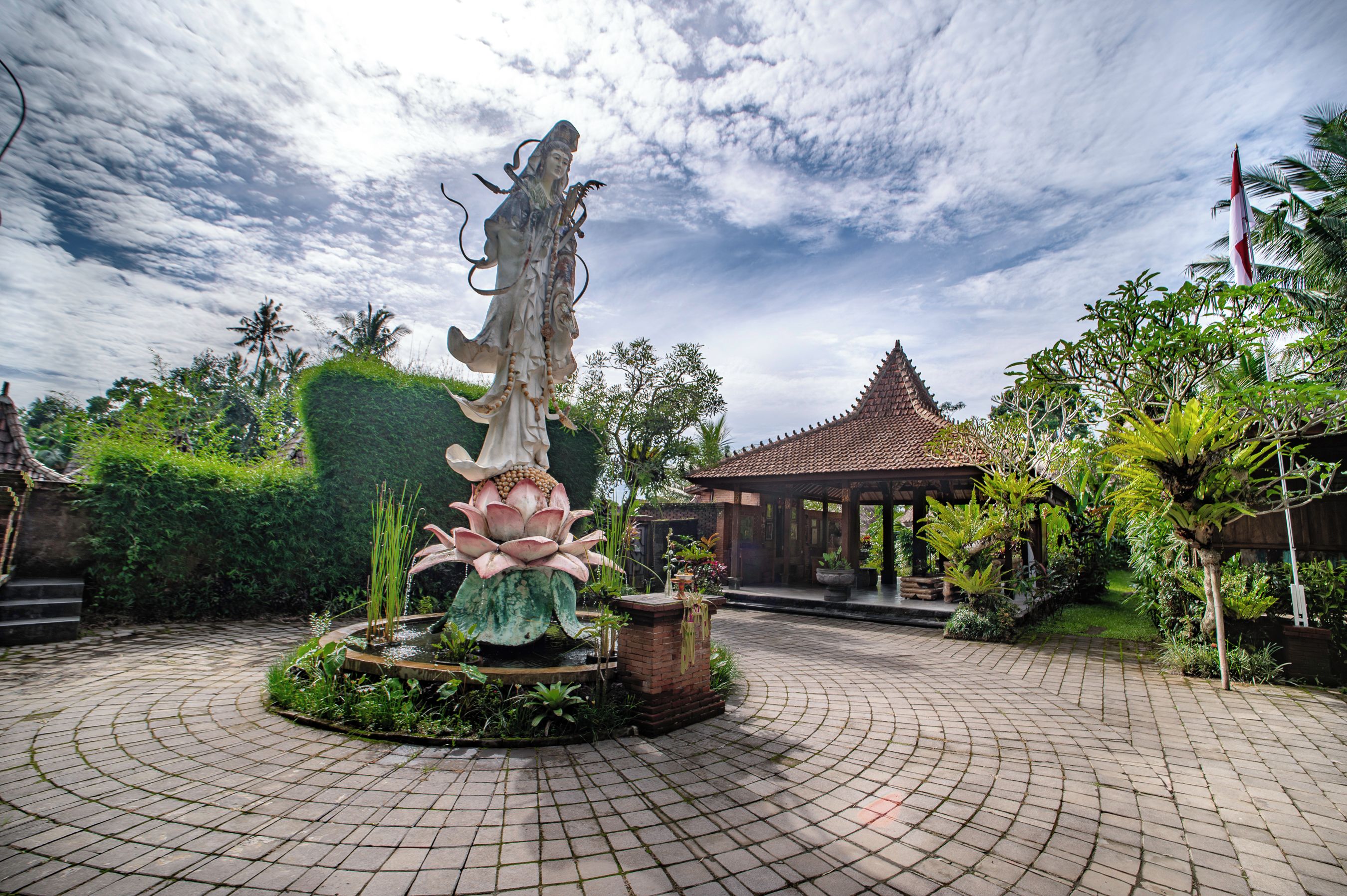A garden with a central fountain, a gazebo, and a tiled pathway.