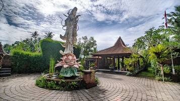 A garden with a central fountain, a gazebo, and a tiled pathway.
