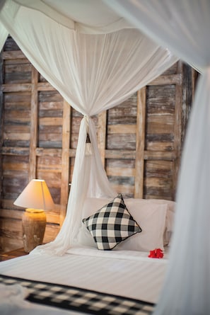 Un lit à baldaquin, un coussin à carreaux, un vase et une lampe.