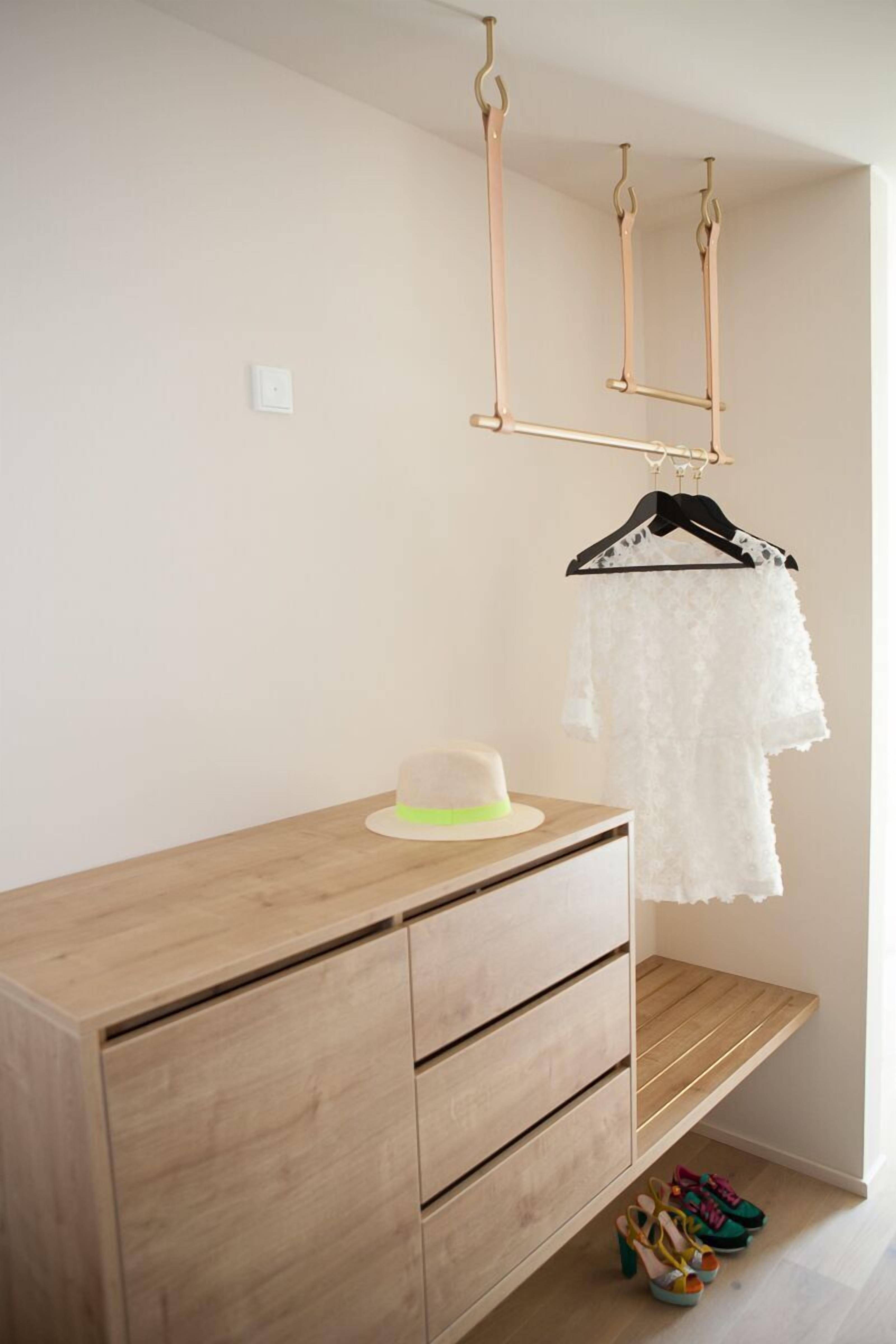 Eine Holzkommode mit Schubladen, ein Hut darauf und ein weißes Spitzenkleid an einem schwarzen Kleiderbügel.