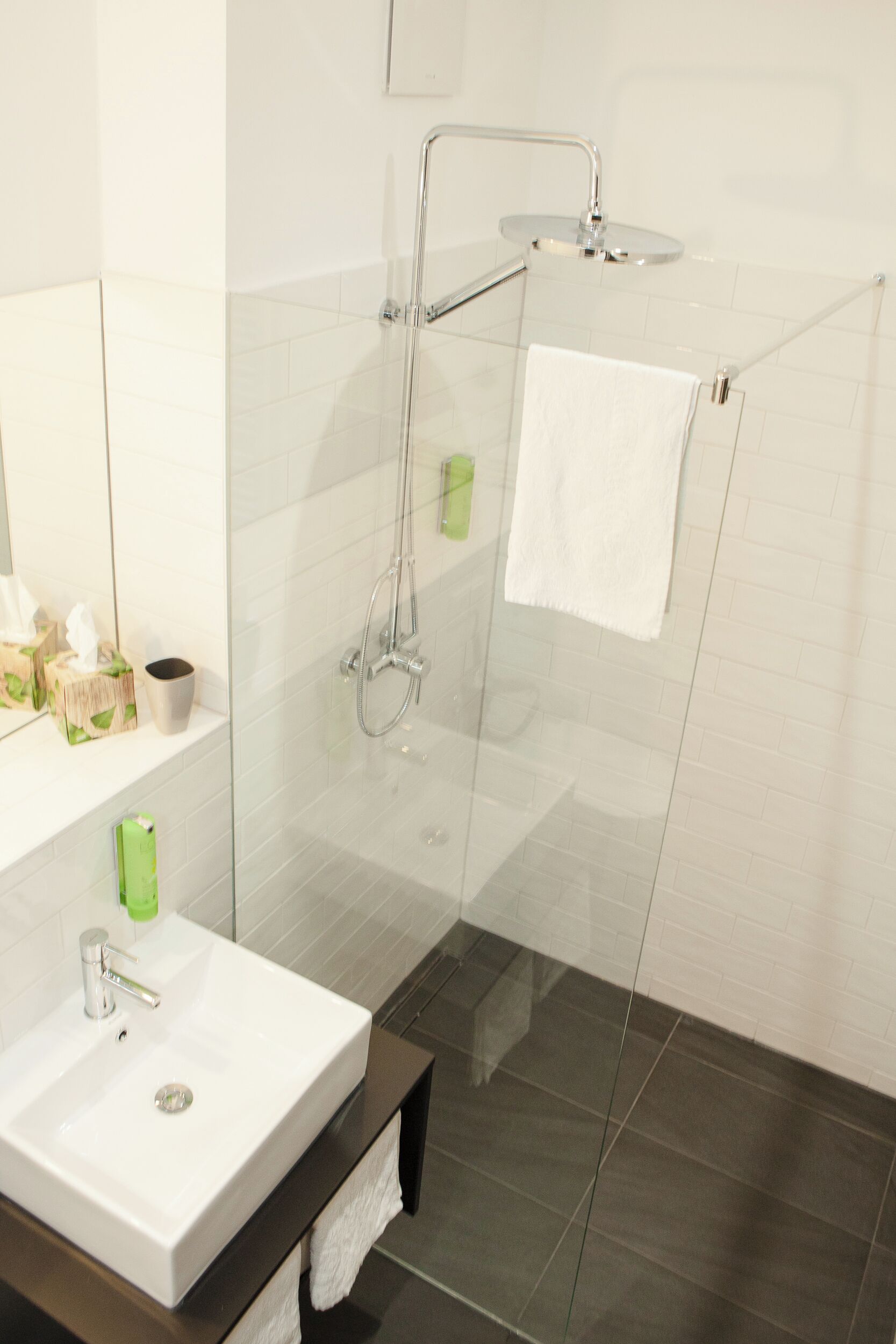 Een moderne badkamer met een douchecabine van glas, een wit wastafelmeubel en een spiegel.