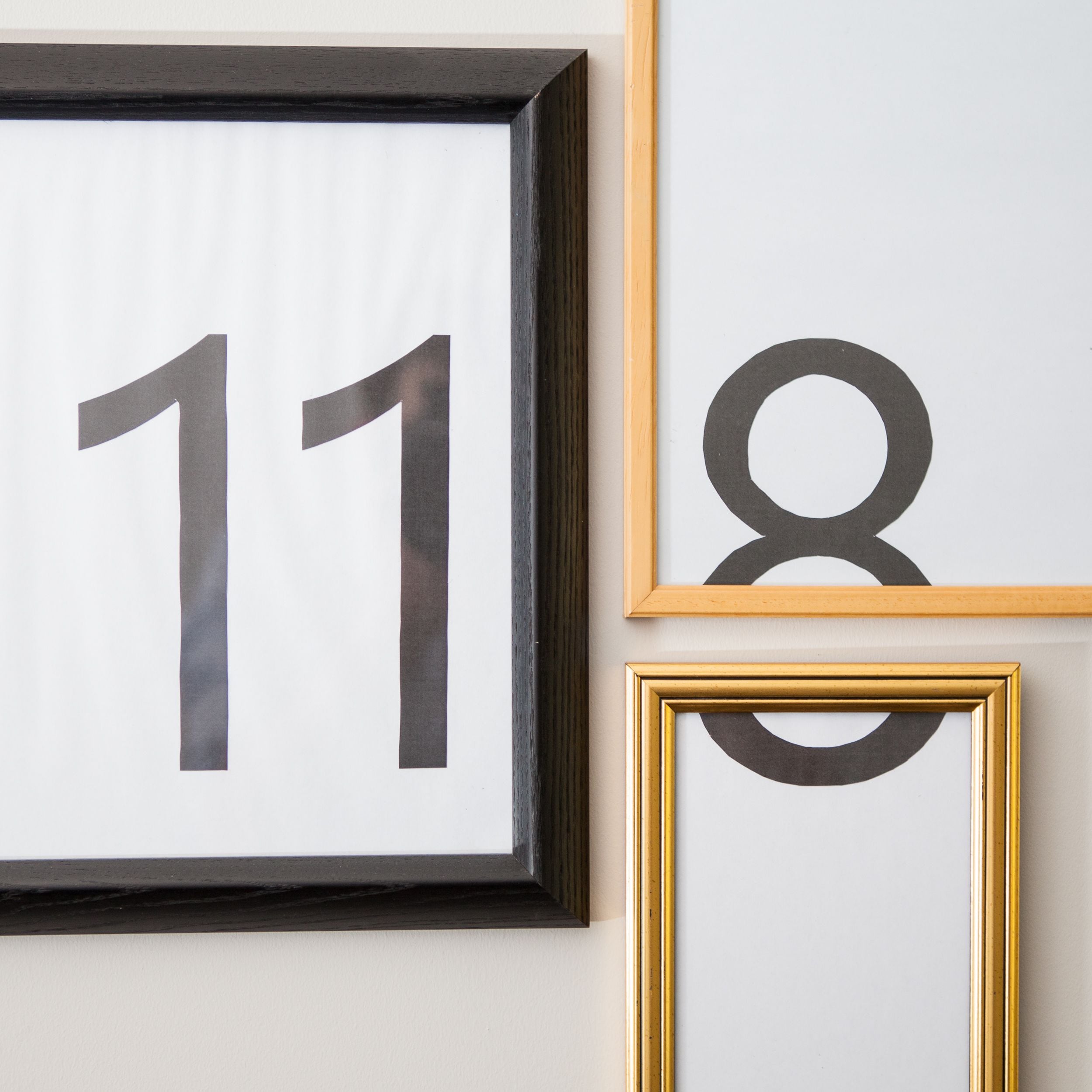 Tres números enmarcados, 11, 8 y 18, en una pared.