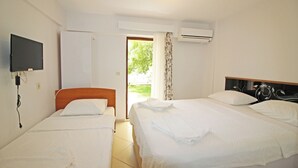 A hotel room with two beds, a TV, an air conditioner, and a view of the outdoors. - Arsipel Hotel (Bozcaada)