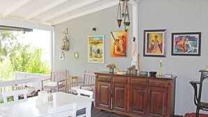 A dining area with a wooden table and chairs, a wooden cabinet, and artwork on the wall. - Arsipel Hotel (Bozcaada)