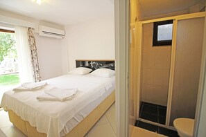 Quarto com cama, chuveiro e vaso sanitário.