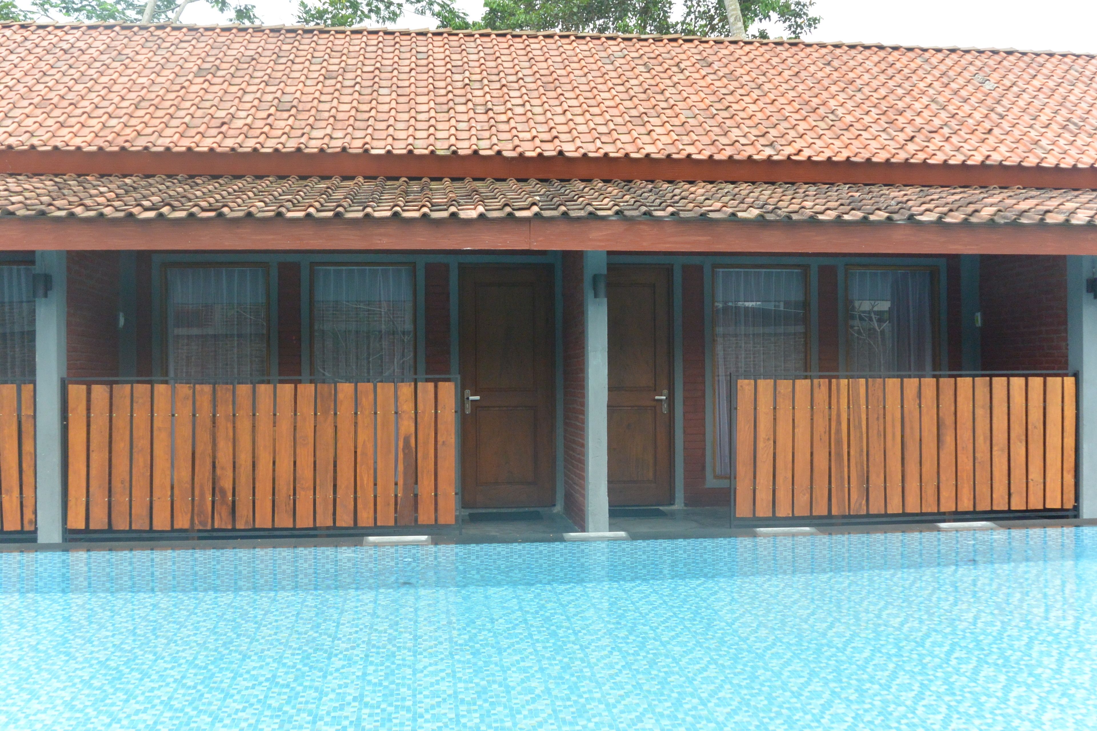 A swimming pool with a tiled roof and wooden fences.