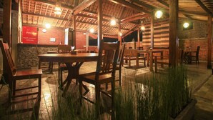 A rustic wooden dining area with brick walls and a thatched roof.