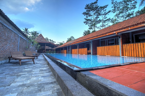 Relax by the serene pool surrounded by a stone pathway and comfortable lounge chairs.