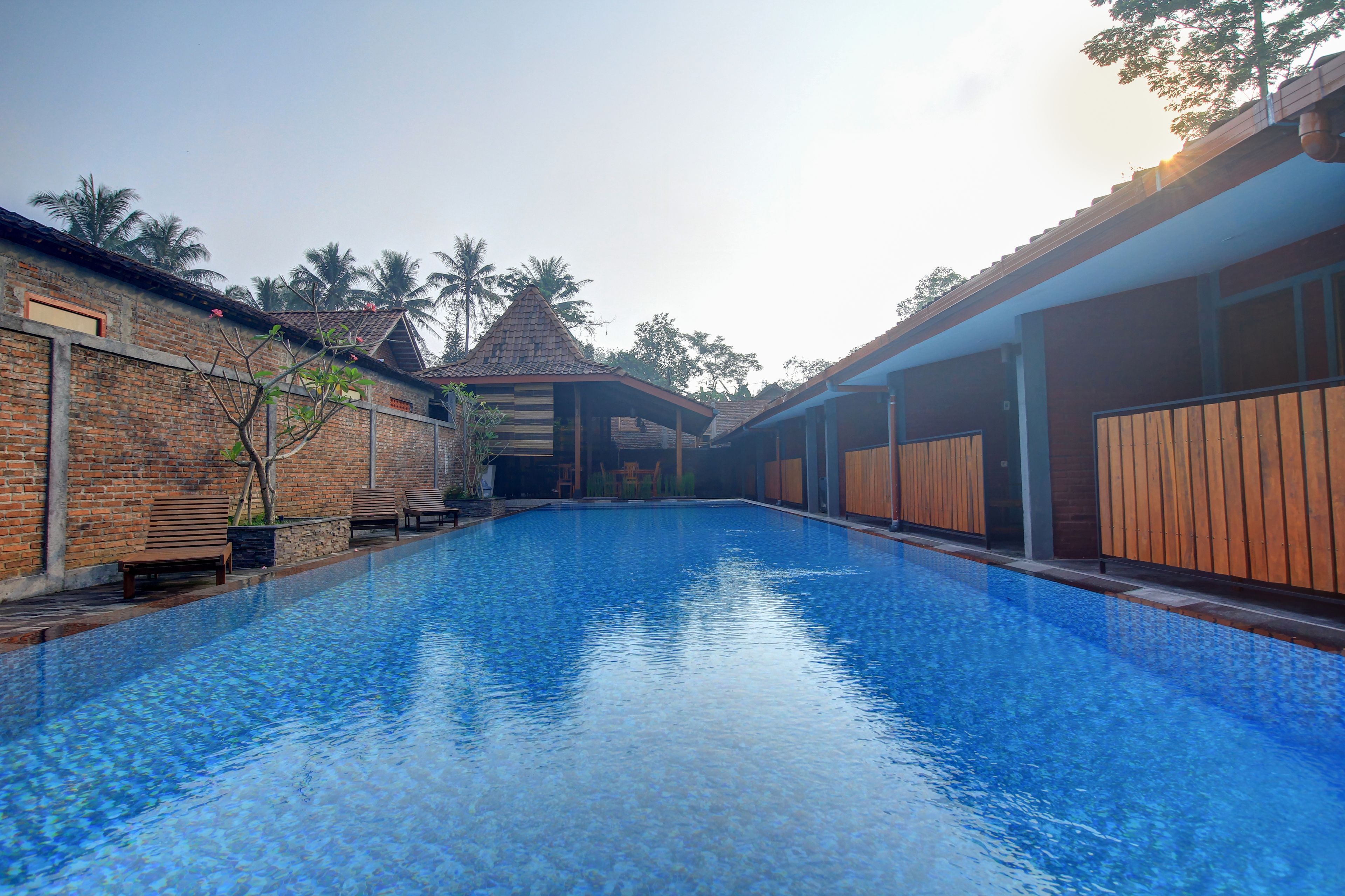 A swimming pool with a clear blue water surface, surrounded by brick walls and wooden fences.