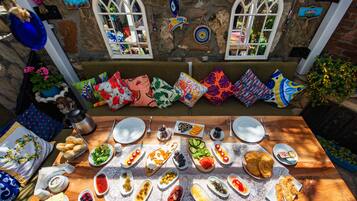 A table set with various dishes and a stone wall with windows.
