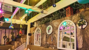 A cozy room with a stone wall, a wooden staircase, and a cushioned seating area. - Ebruli Hotel (Bozcaada)