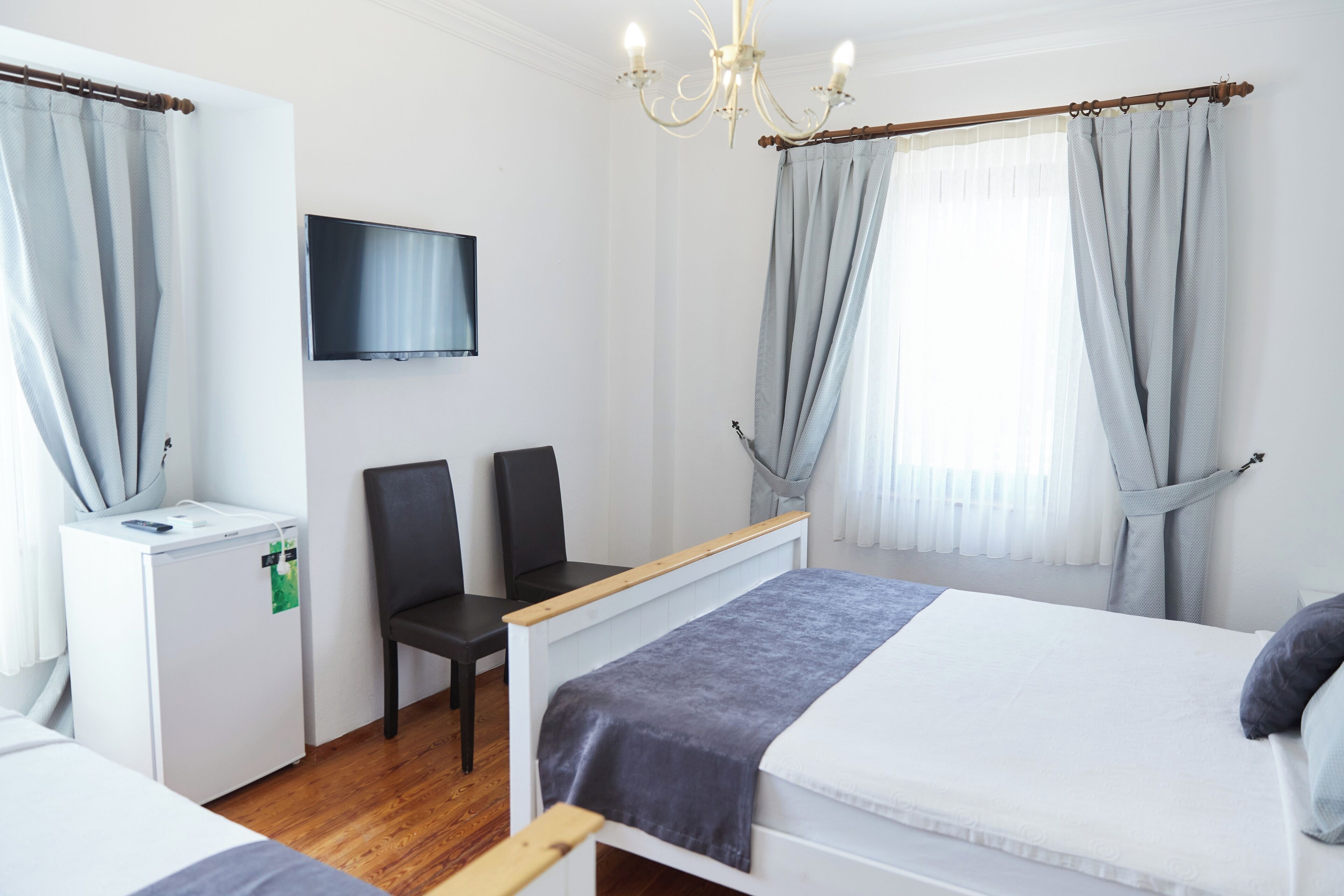 Une chambre d’hôtel avec un lit, un bureau, une chaise, une télévision et une fenêtre avec des rideaux.