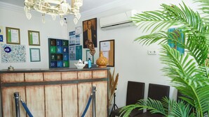 A reception area with a wooden counter, framed certificates, and a plant. - Ebruli Hotel (Bozcaada)