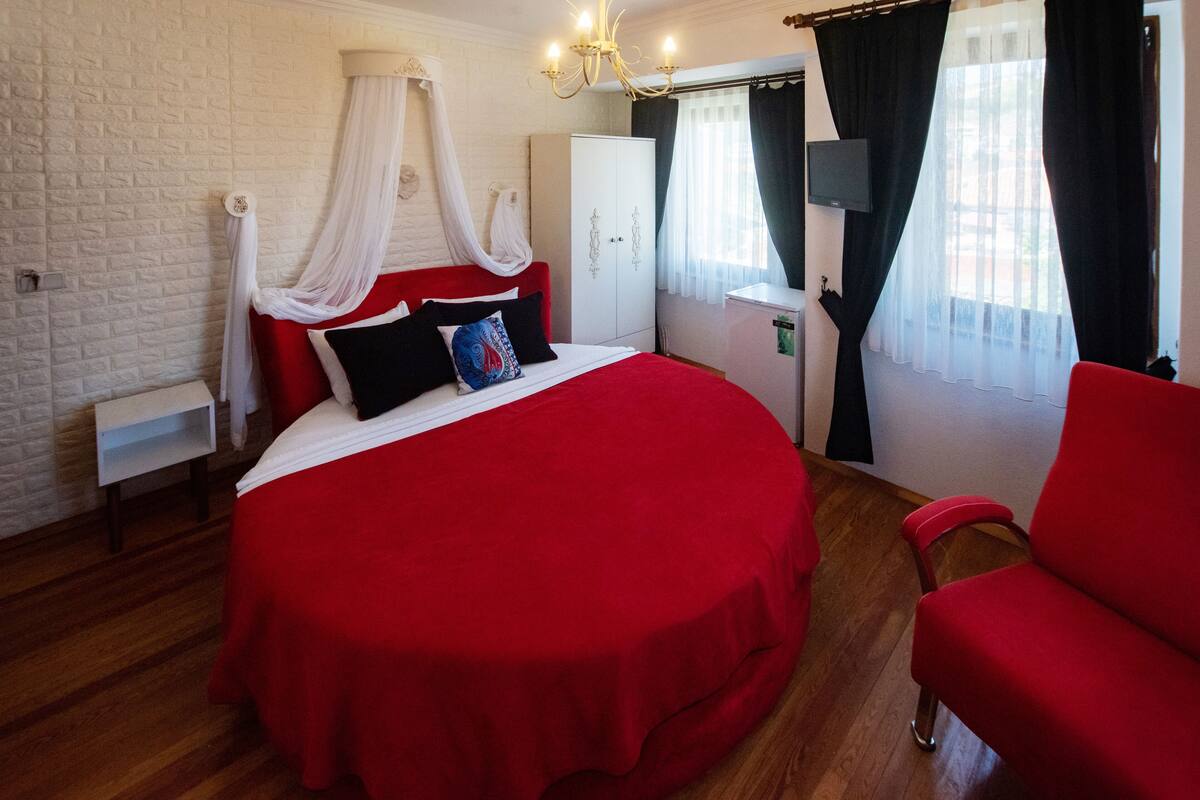 A bedroom with a large bed, a wardrobe, a desk, and a chair.