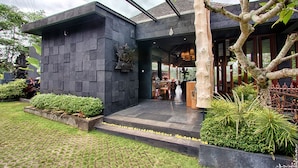 Un edificio moderno con fachada de piedra, entrada de madera y un jardín bien cuidado.