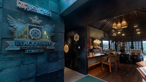 Un interior de restaurante con un diseño moderno y oscuro, que incluye una zona de bar y muebles de madera.