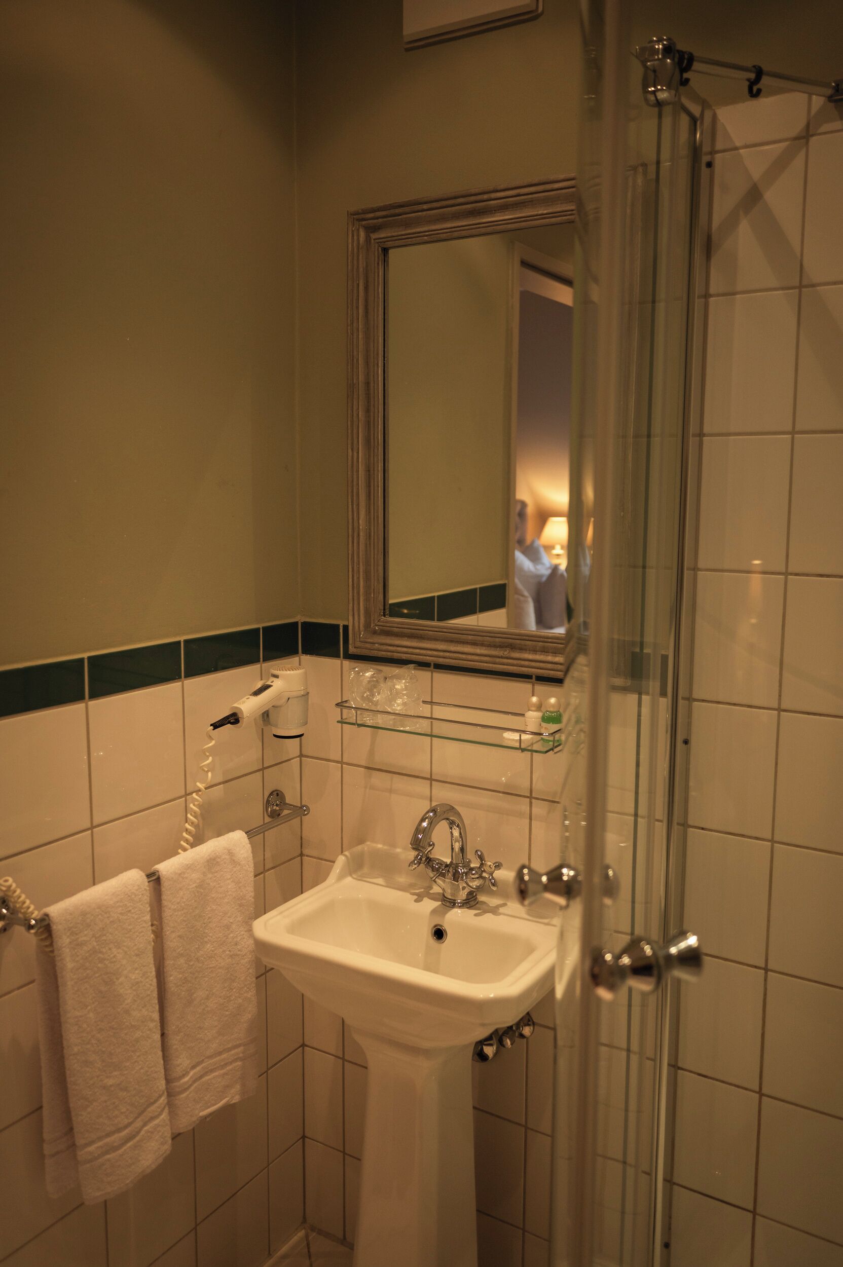 A bathroom with a white sink, a mirror, and a glass shower enclosure.