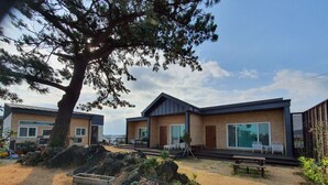 A modern outdoor area with two cabins, each with a patio and seating. - Wind Jeju Cafe & Pension (Seogwipo)