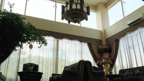 Um quarto espaçoso com uma grande janela, um lustre e uma televisão de tela plana na parede.
