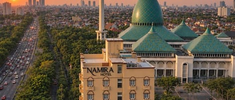 A hotel with multiple green domed buildings, a prominent minaret, and a cityscape in the background.