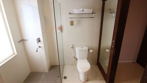 Een moderne badkamer met een douche met glazen wand, een toilet en een plank met handdoeken.