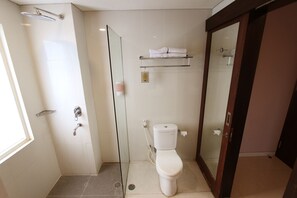 Un baño moderno con ducha de vidrio, inodoro y repisa con toallas.