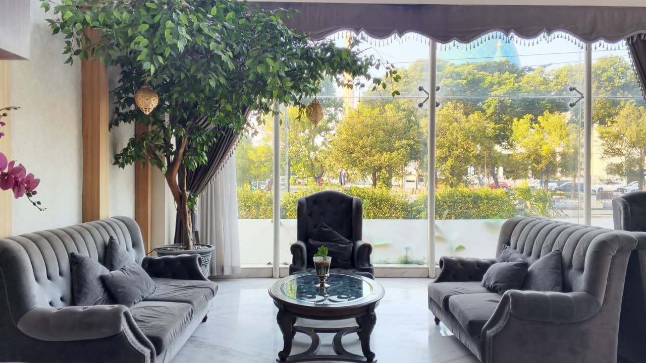 A room with two sofas, a table, and a large window with a view of trees and buildings.