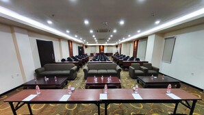 Un salón de conferencias con filas de mesas, sillas y sofás.