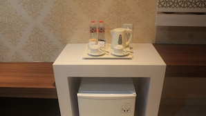 Een kleine kitchenette met een koffiezetapparaat, twee waterflesjes en een kleine koelkast.