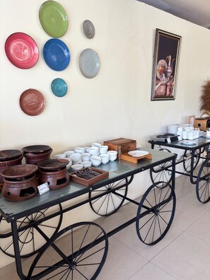 Un espace repas avec une longue table, de nombreuses assiettes, des bols et quelques objets décoratifs accrochés au mur.