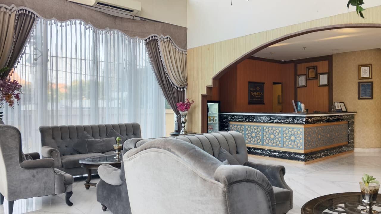 Un hall de hotel con una recepción, sofás y una mesa de centro.