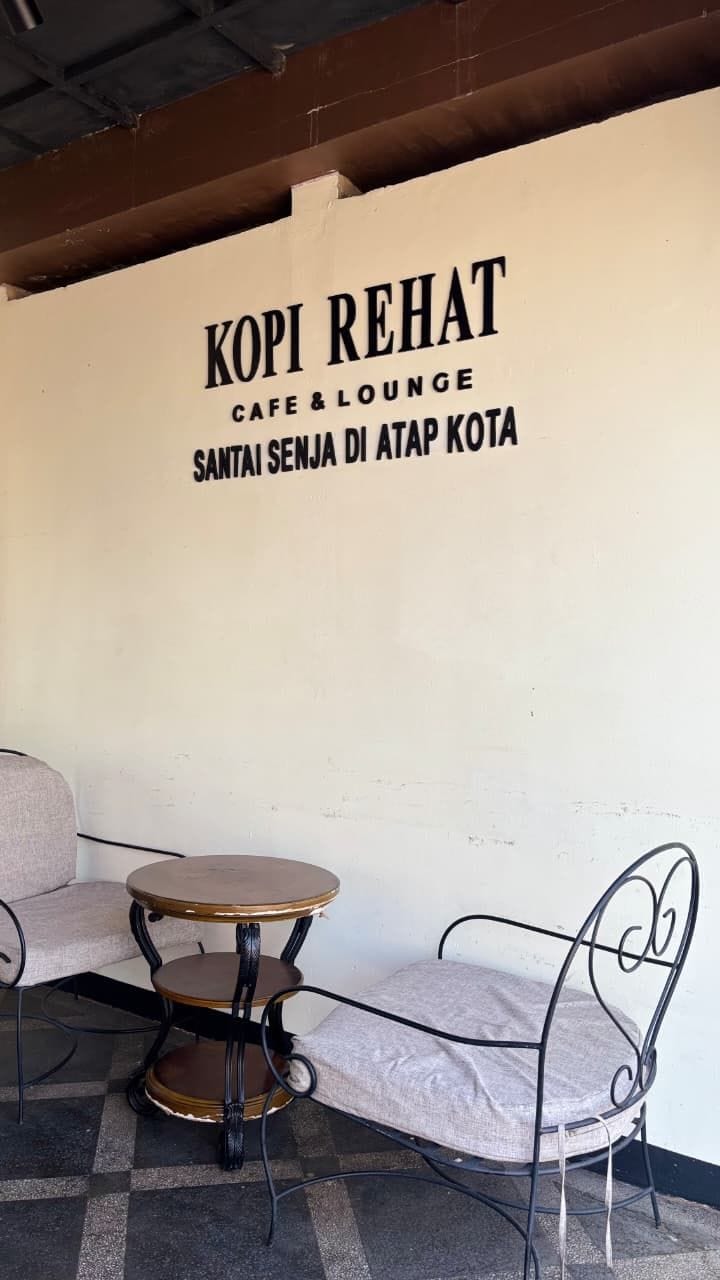 Um café chamado 'KOPI REHAT' com uma placa indicando que é café e lounge.