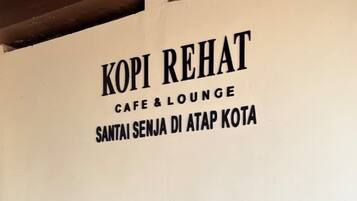 Um café chamado 'KOPI REHAT' com uma placa indicando que é café e lounge.