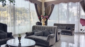 A modern living room with two grey sofas, a glass coffee table, and a decorative vase with flowers.