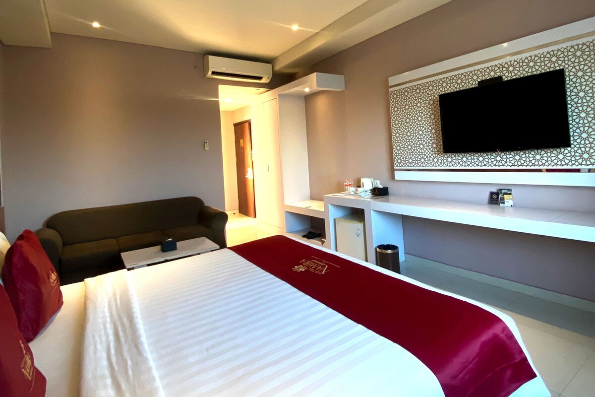 Una habitación de hotel con una cama, televisión, escritorio y una silla.