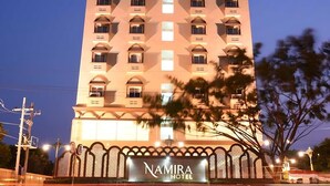 Um edifício alto de hotel com uma placa na entrada que diz 'Namira Hotel'.