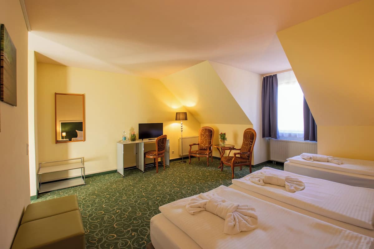 Een hotelkamer met twee bedden, een bureau, een stoel, een televisie en een raam met gordijnen.