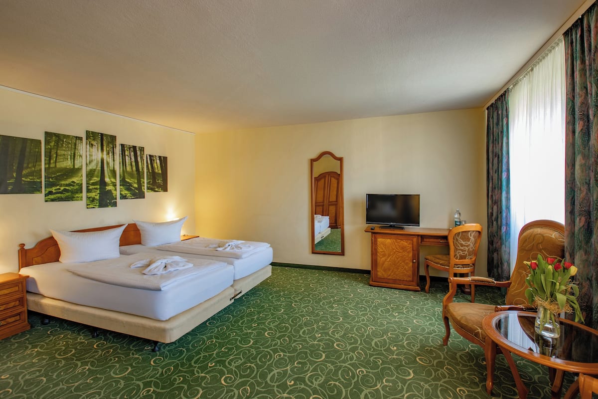 Een hotelkamer met een groot bed, twee nachtkastjes, een bureau met een stoel, een televisie en een spiegel.