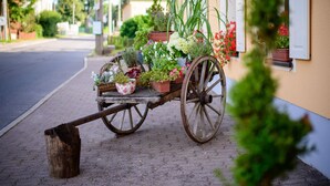 Un carruaje de madera con plantas en macetas estacionado en una calle adoquinada.