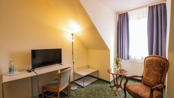 Een hotelkamer met een bureau, stoel, televisie, lamp en uitzicht op de omgeving.
