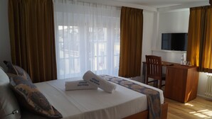 A hotel room with a large bed, a desk, a chair, a television, and curtains. - Hotel Old Town (Zürich)